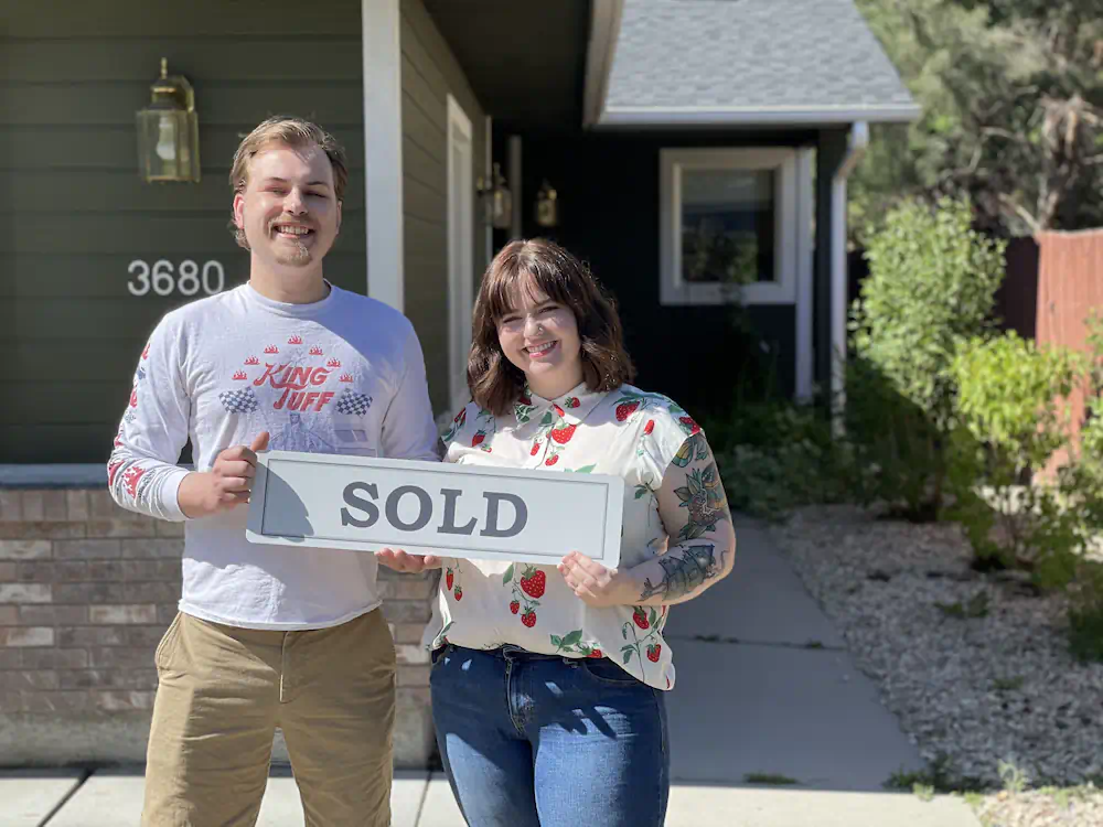 Ariel & Jared holding a SOLD sign after a successful home purchase in NW Boise.