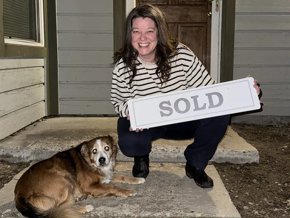 Thrilled Buyer and her dog holding a sold sign in front of her first house in Meridian, ID.